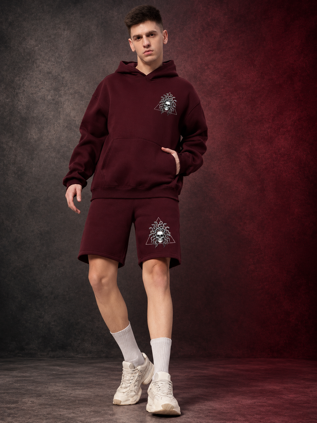Man wearing GORGON SKULL PRINTED FLEECE CO-ORD SET WINE hoodie and shorts with skull graphic streetwear design