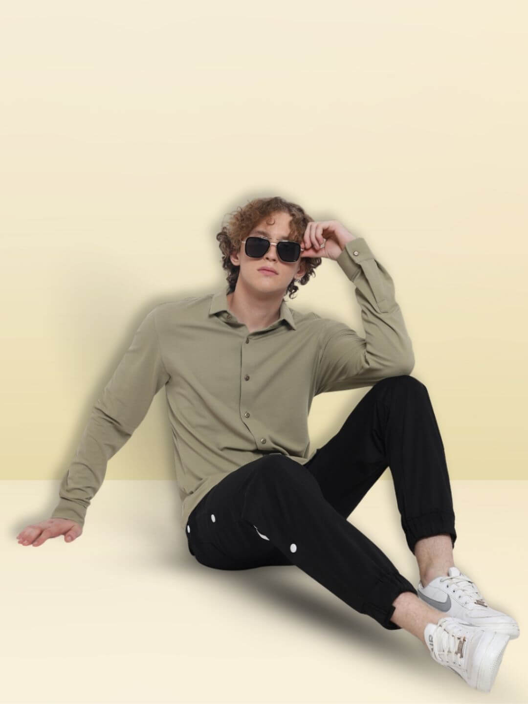 Model wearing GRAVEL SPORTY PIQUE SHIRT, full sleeve, slim fit, curved hem, lounging comfortably in stylish attire.