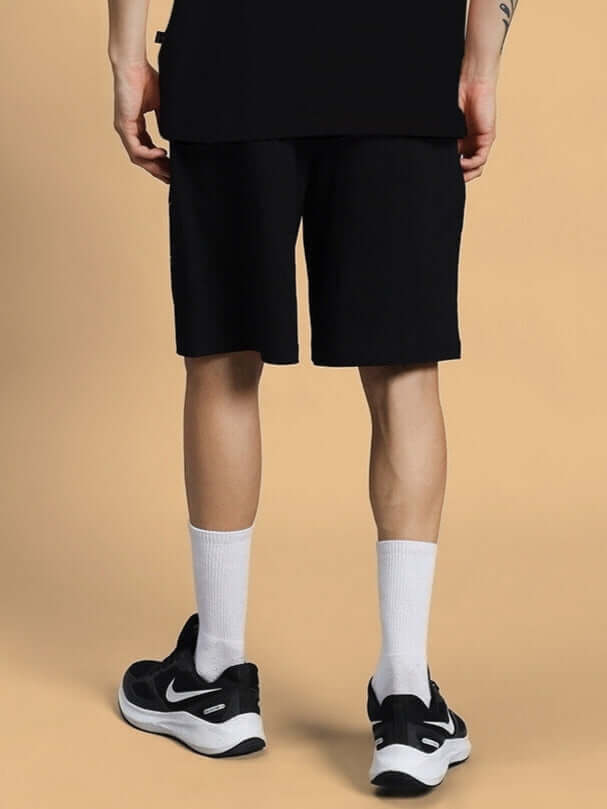 Rear view of person wearing GREAT PRINTED SUMMER SHORTS BLACK with sneakers. Custom fit available for prepaid orders. Ideal for summer fashion.