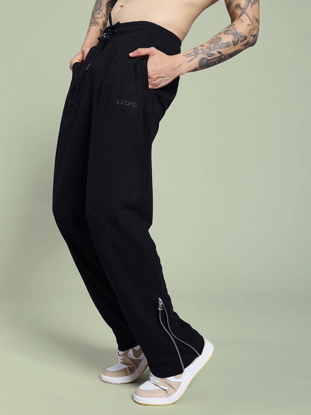 Person wearing JOSS WINS RELAXED-FIT JOGGER BLACK, demonstrating style and comfort on green background.