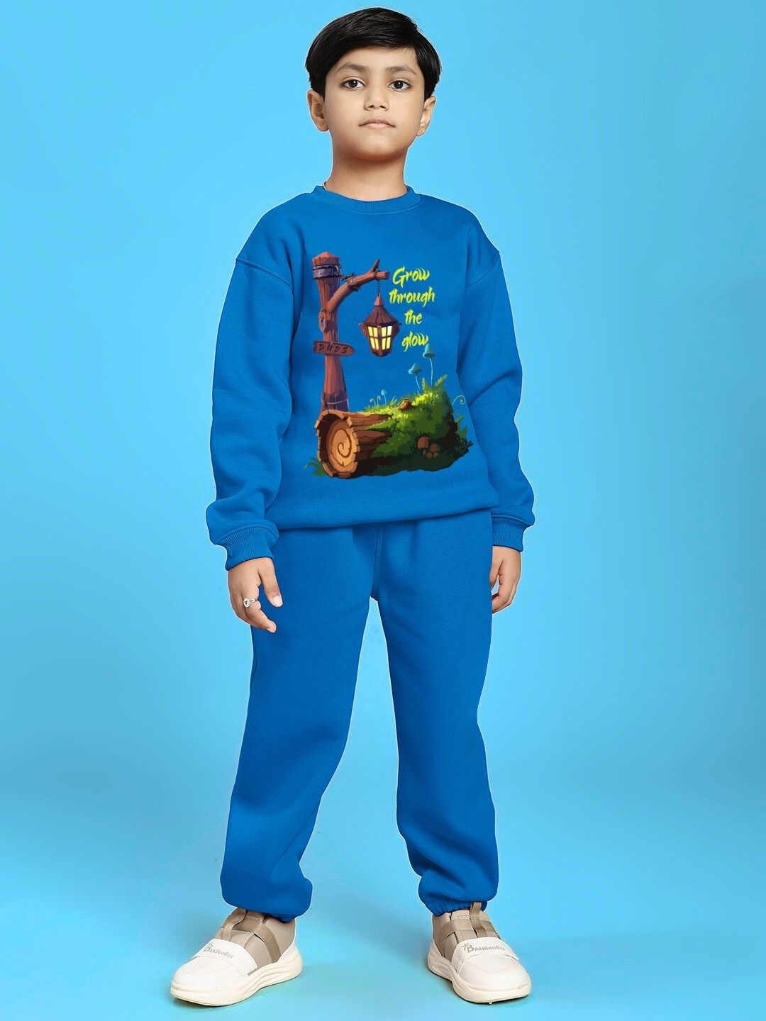 Child wearing GROW AND GLOW PRINT FLEECE CO-ORD FOR BOYS AND GIRLS BLUE standing against blue background.