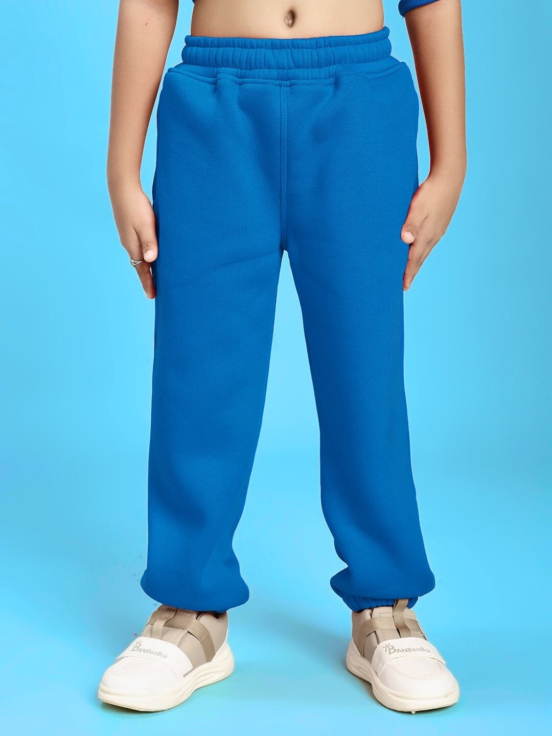 GROW AND GLOW FLEECE JOGGER FOR BOYS AND GIRLS BLUE with child wearing blue joggers and white sneakers on a blue background
