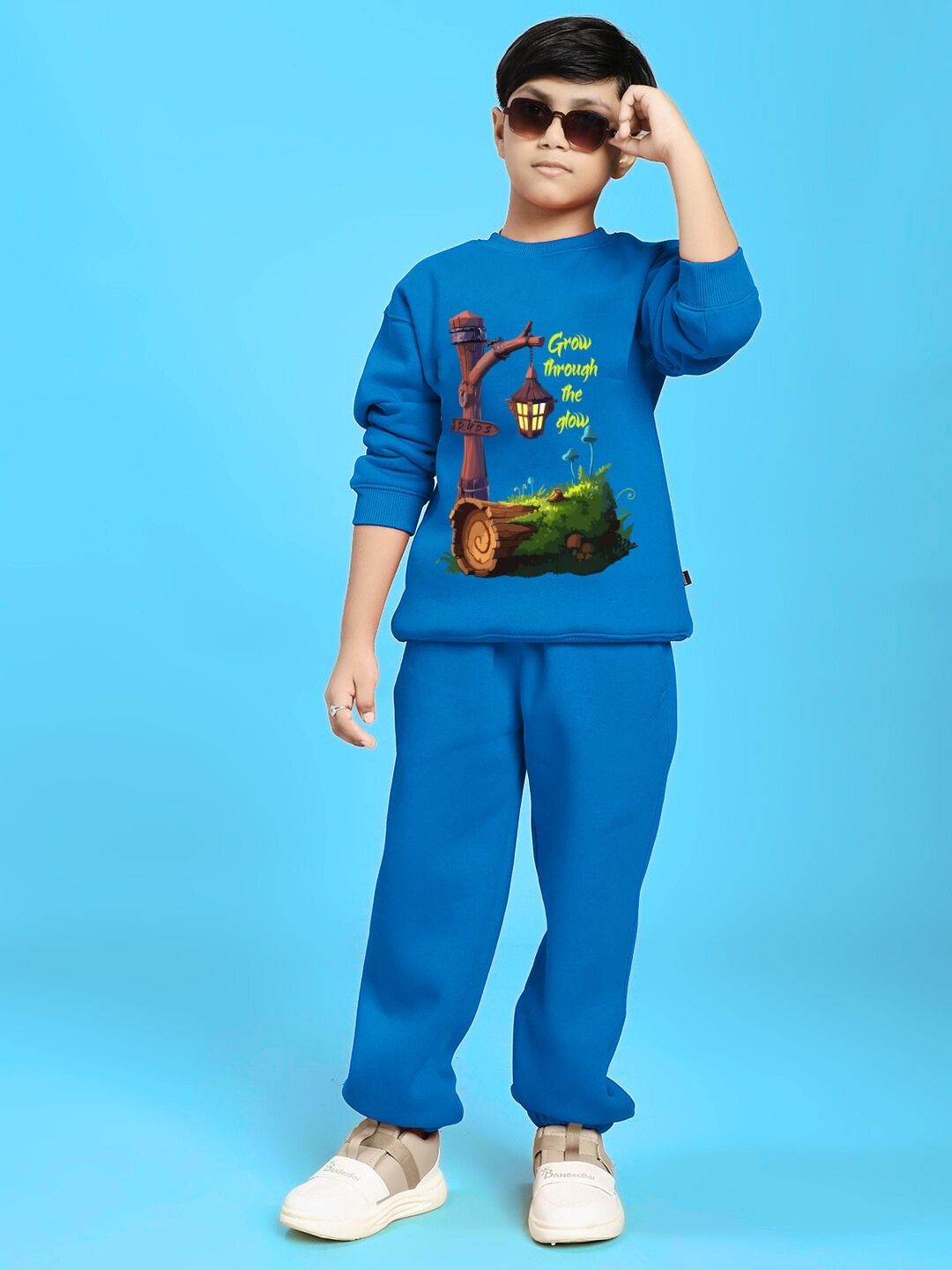 Child wearing GROW AND GLOW PRINT FLEECE CO-ORD FOR BOYS AND GIRLS BLUE outfit against blue background.