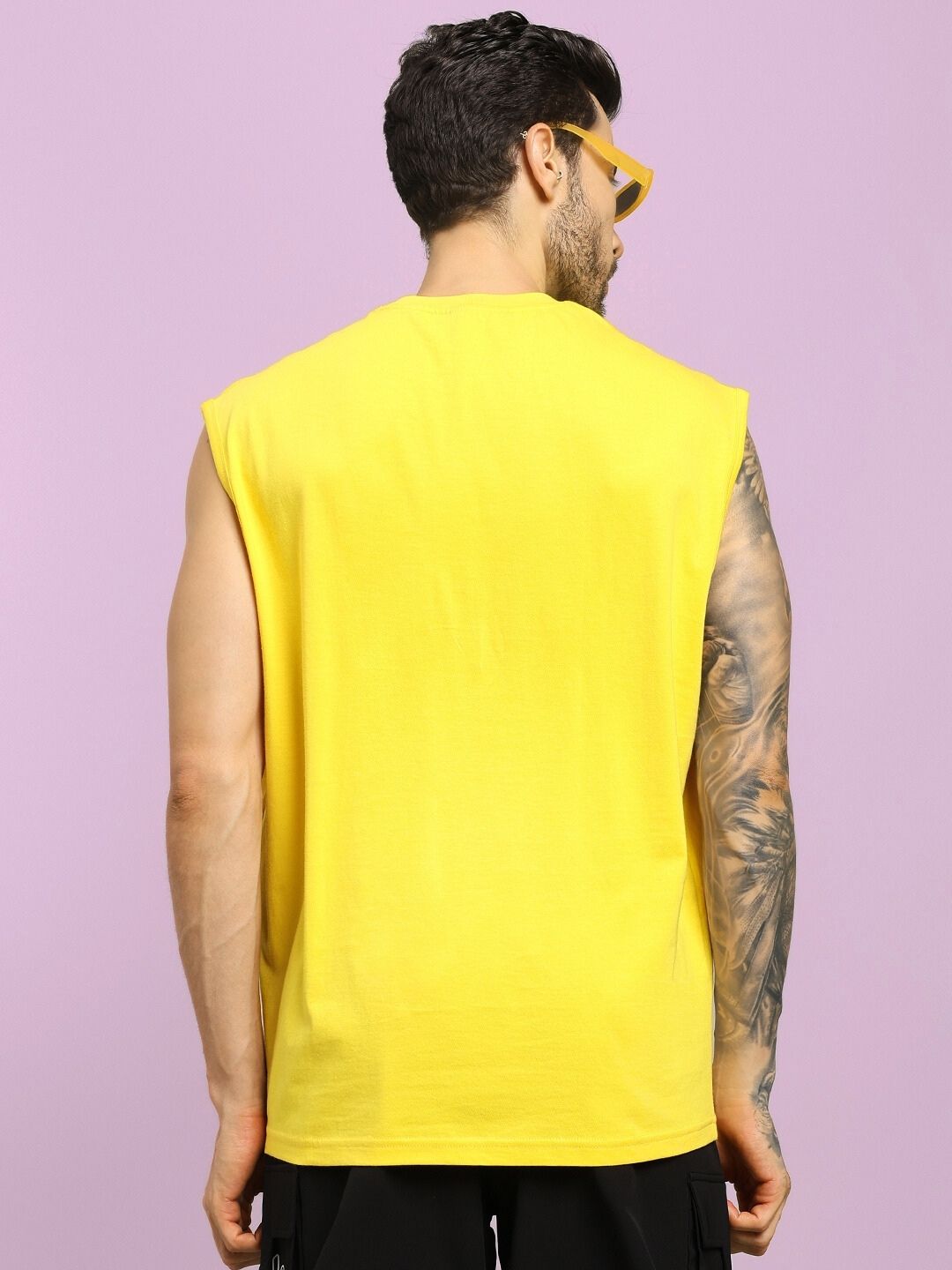 Rear view of man wearing HAPPY SKULL PRINTED GYM T-SHIRT YELLOW, showcasing bright color and sleeveless design.