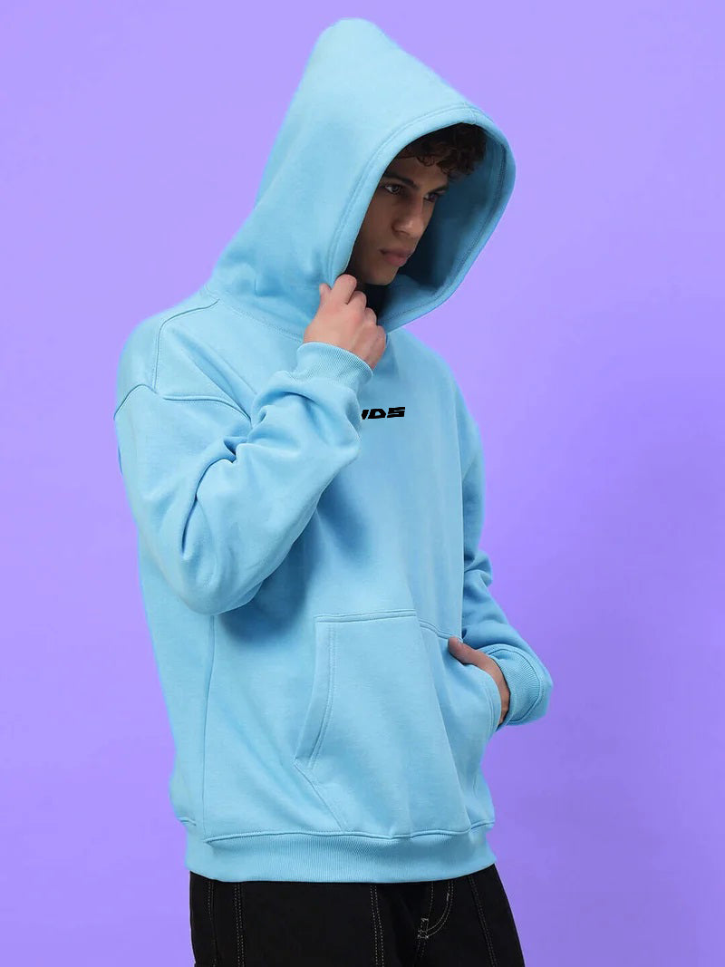 Person wearing HEARTBREAK OVERSIZED FLEECE HOODIE LIGHT BLUE against purple background.