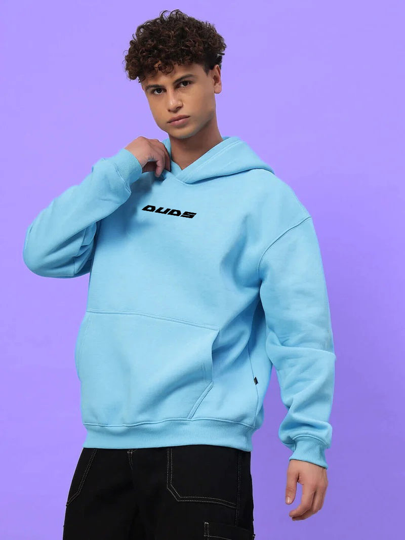 Model wearing HEARTBREAK OVERSIZED FLEECE HOODIE LIGHT BLUE with casual pose.