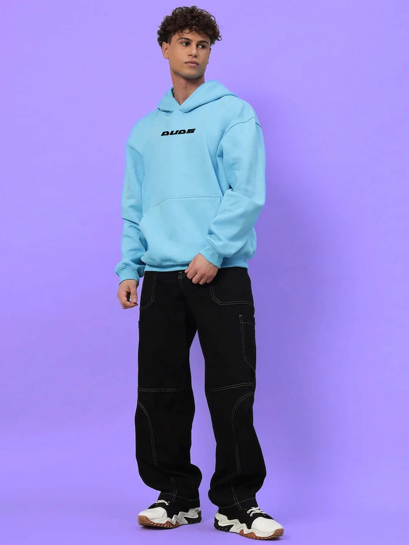 Model wearing the HEARTBREAK OVERSIZED FLEECE HOODIE LIGHT BLUE on a purple background
