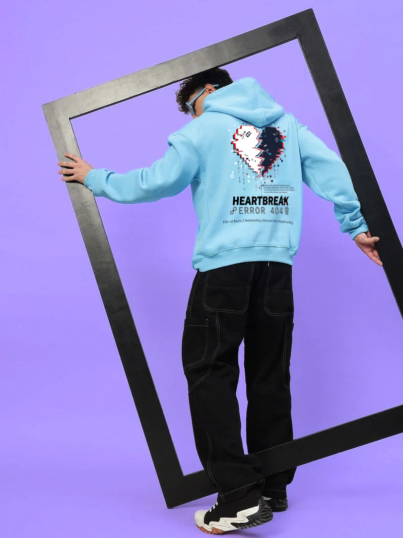 Person wearing HEARTBREAK OVERSIZED FLEECE HOODIE LIGHT BLUE with frame against purple background