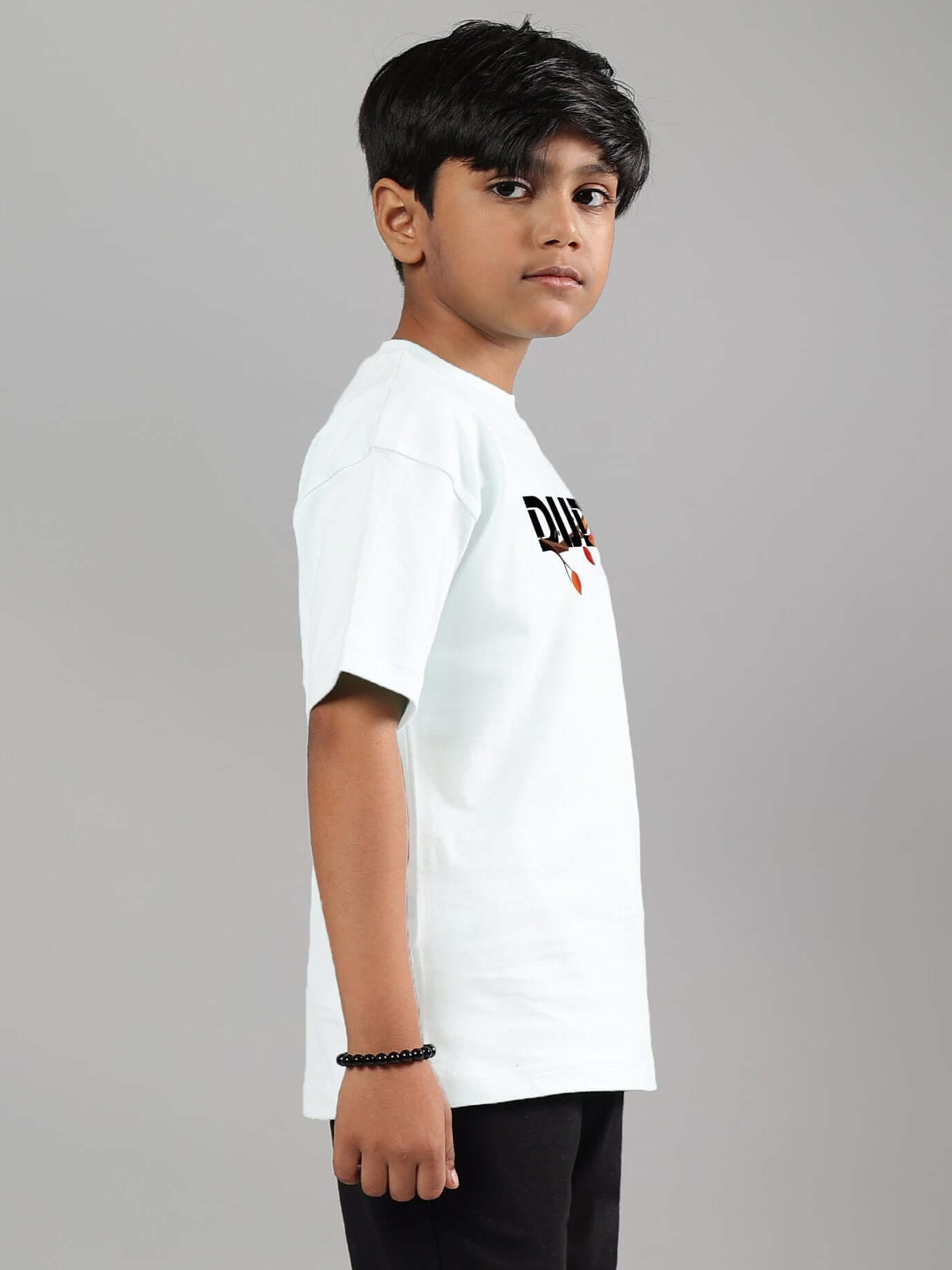 Young boy wearing a white Hedwig T-shirt designed for boys and girls, by DUDS, side view, showcasing casual style and comfort.