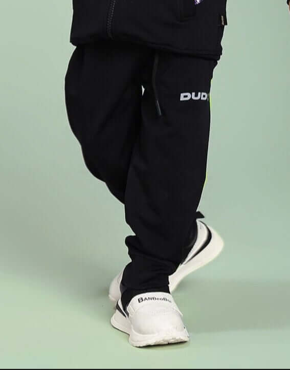 Child wearing HIGH PERFORMANCE JOGGER FOR BOYS AND GIRLS BLACK stepping forward, showcasing durability for active kids.