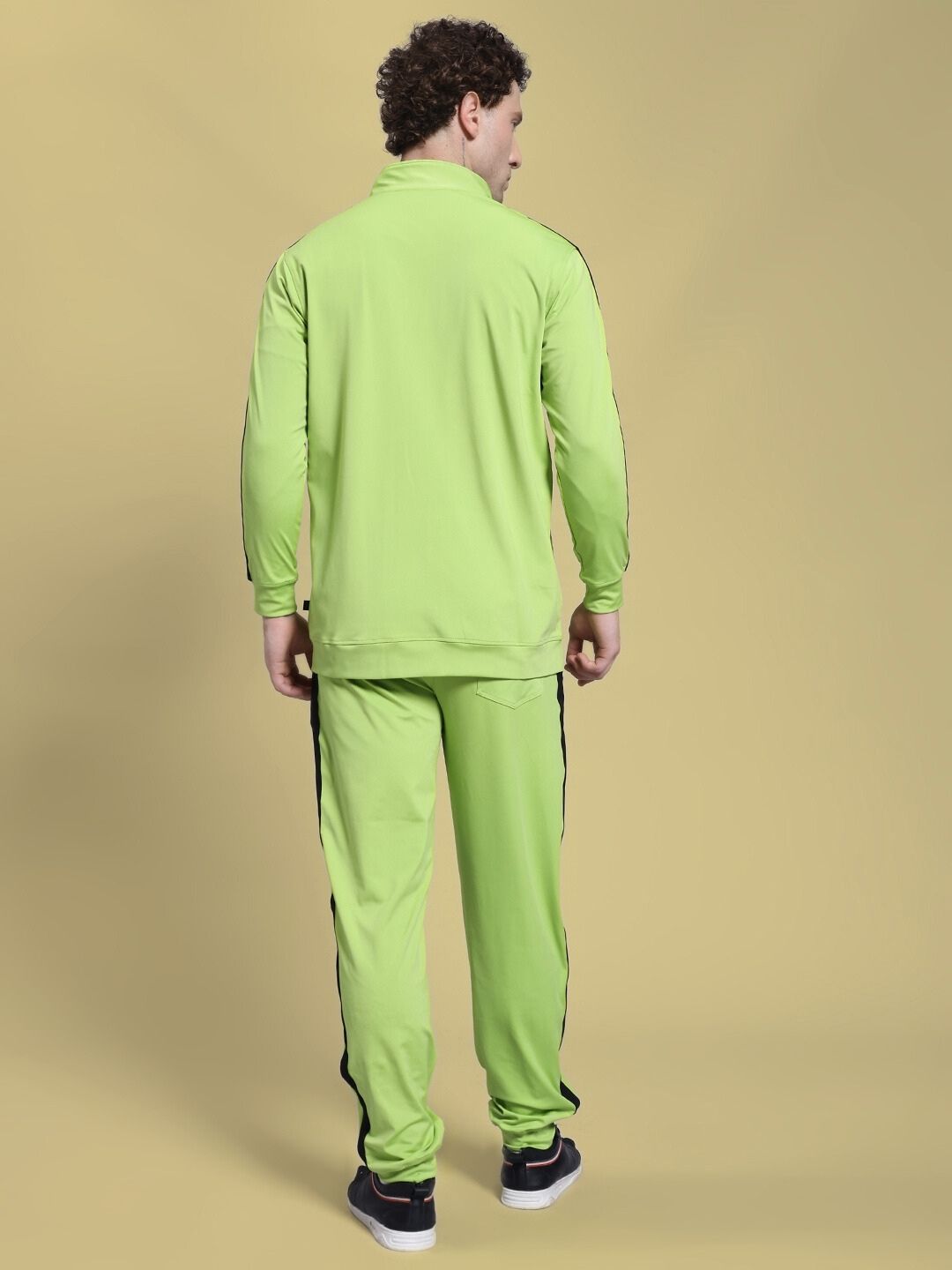 Rear view of man wearing HIGH PERFORMANCE CO-ORD SET NEON GREEN with zip-up hoodie and tapered joggers against a neutral background.