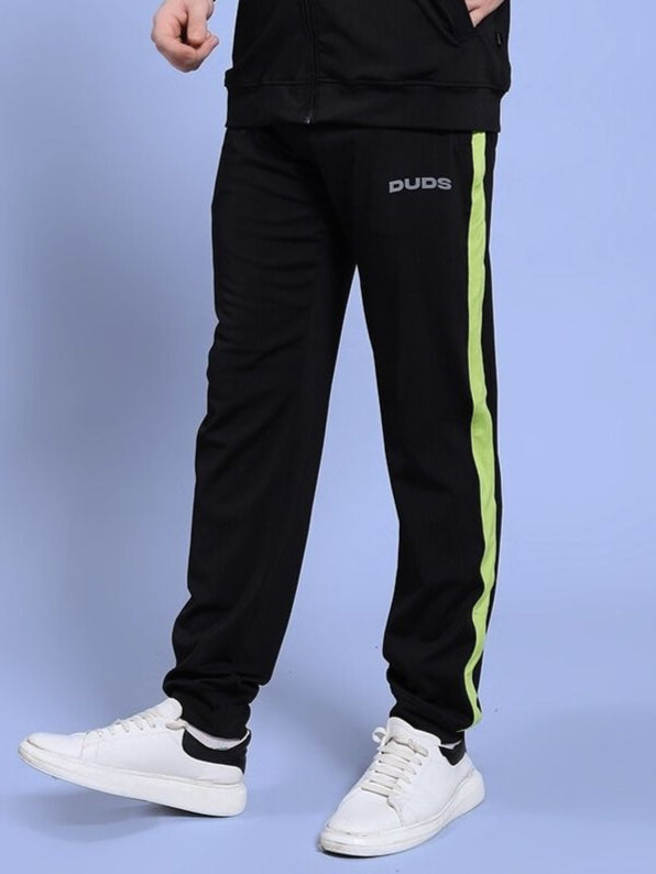 Person wearing HIGH PERFORMANCE RELAXED FIT JOGGER BLACK with green stripe, showcasing comfort and style indoors.