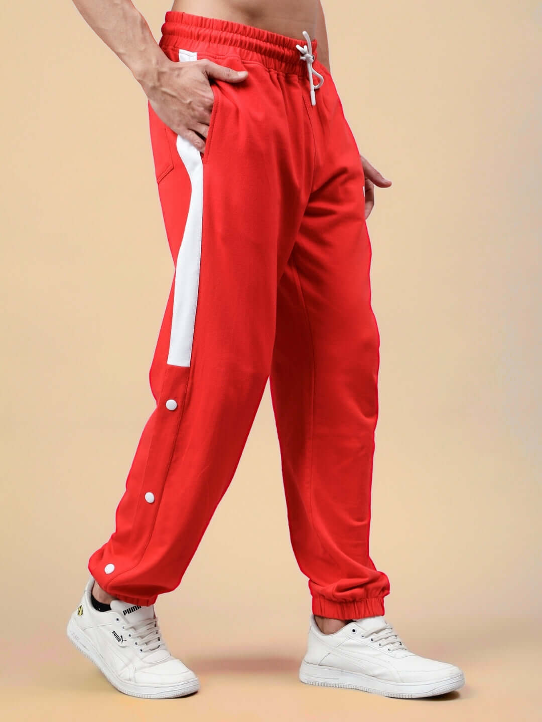 Man wearing red-white joggers with drawstring, made by DUDS, featuring a sleek side stripe design and customizable size options.
