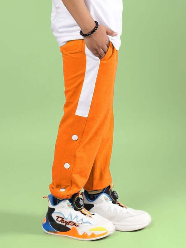 HIGH POINT JOGGER FOR BOYS & GIRLS ORANGE shown with stylish high-top sneakers against a green background.