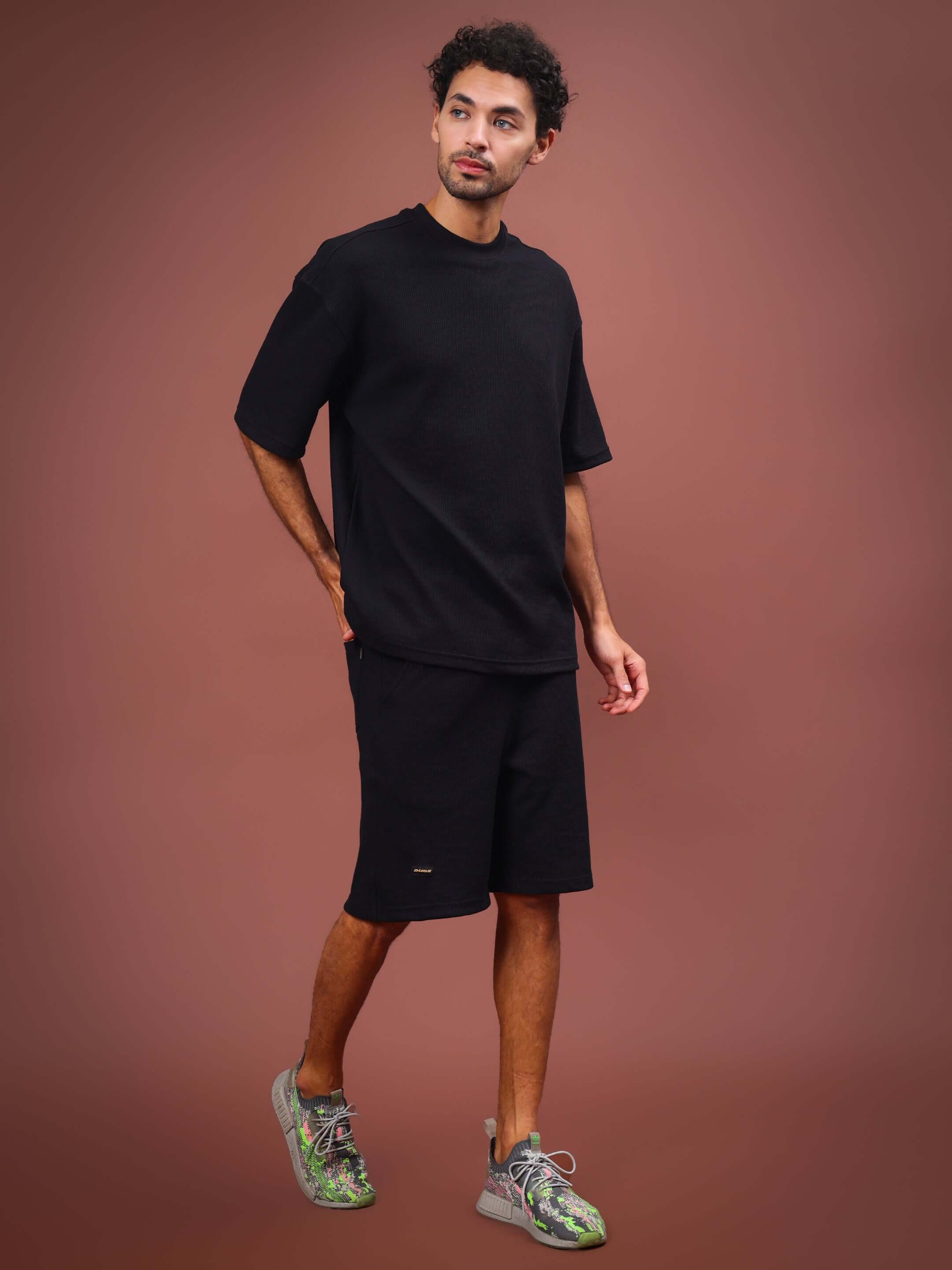 Man wearing HIGHKEY SOLID CO-ORD SET in black, featuring customizable fit options, styled against a neutral backdrop.