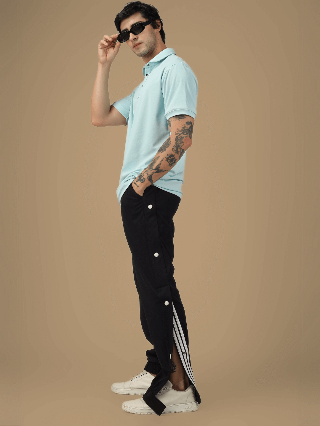Model wearing black HIP HOP JOGGERS with side stripes, styled with a light blue polo shirt and sunglasses, showcasing modern fashion.