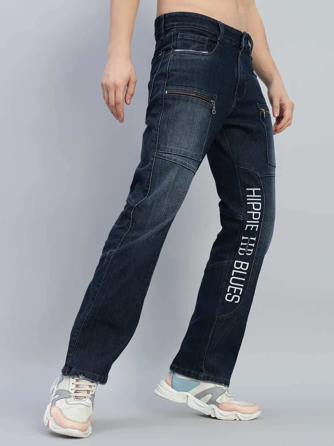 Model wearing Hippie Blue Regular Fit Denim Jeans with zipper pockets and side text, showcasing style and fit.