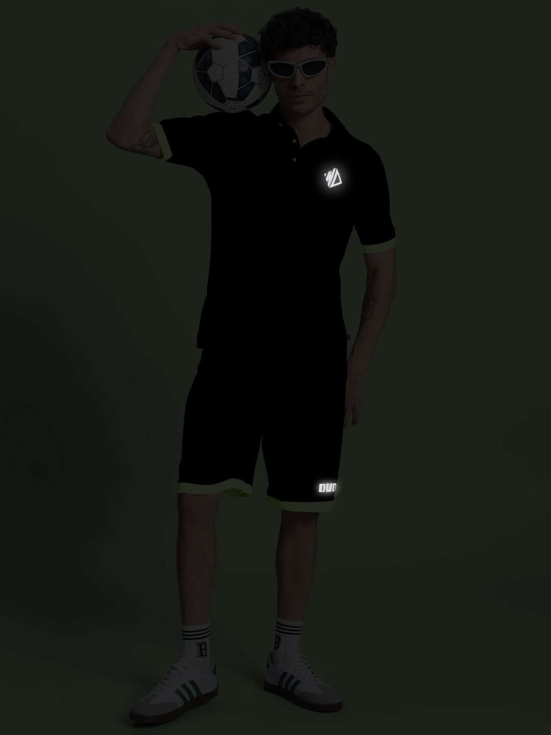 Model wearing HOOKUP REFLECTOR SUMMER CO-ORD SET BLACK holding a soccer ball, showcasing reflective elements, perfect for summer style.