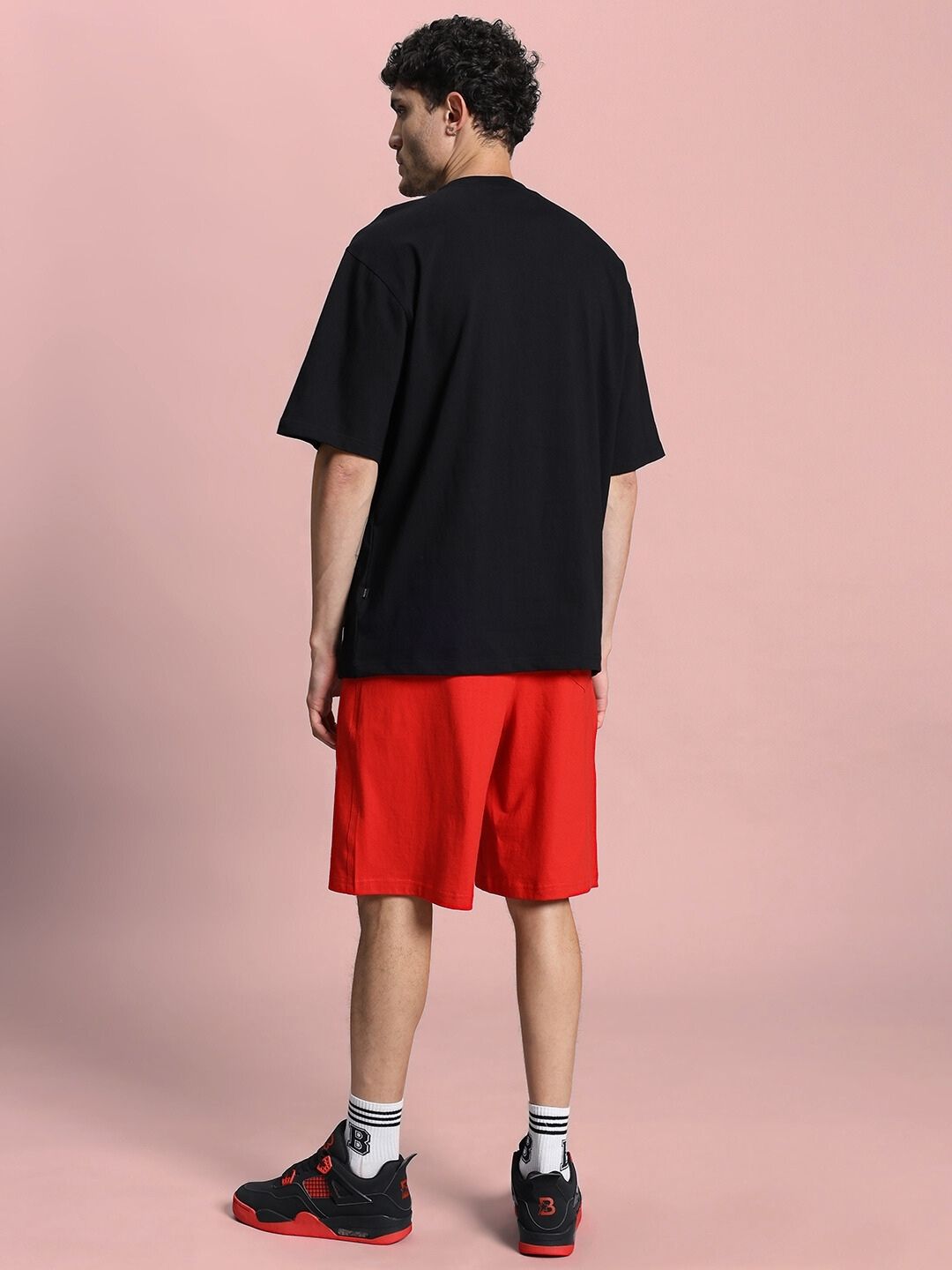 Back view of model wearing HOPE PRINTED OVERSIZED CO-ORD SET BLACK RED with sneakers.