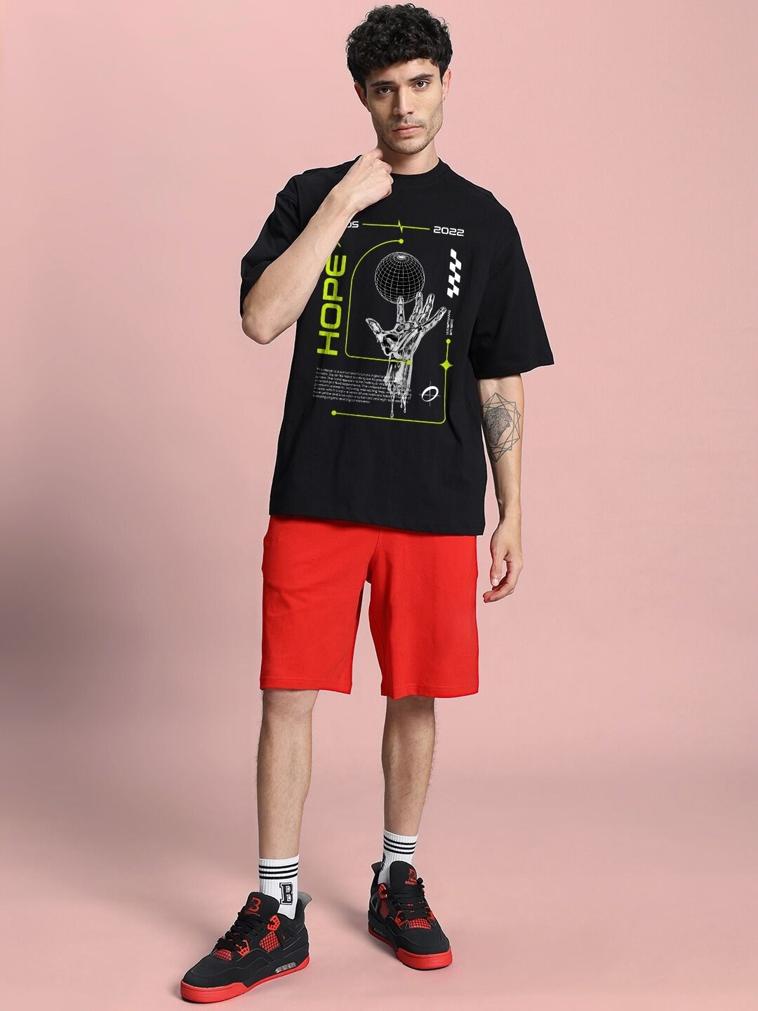 Model wearing HOPE PRINTED OVERSIZED CO-ORD SET BLACK RED with graphic tee and red shorts.