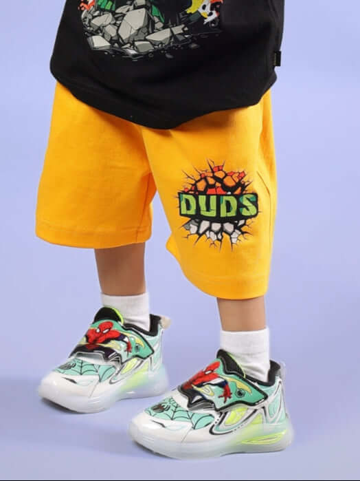 Child wearing yellow Hulk-themed shorts with "DUDS" logo and colorful sneakers.