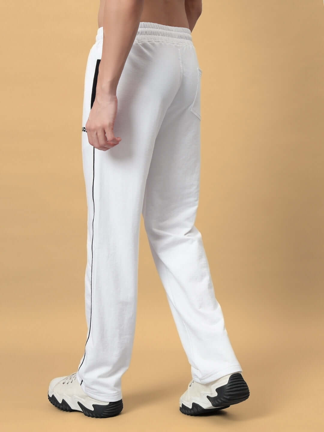 Back view of model wearing white HUNK jogger pants by DUDS, showcasing tailored fit and modern design.