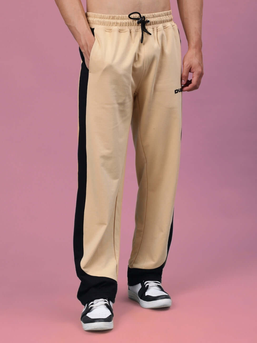Model wearing HURTLE BAGGY JOGGERS in beige and black, featuring custom fit, by DUDS.