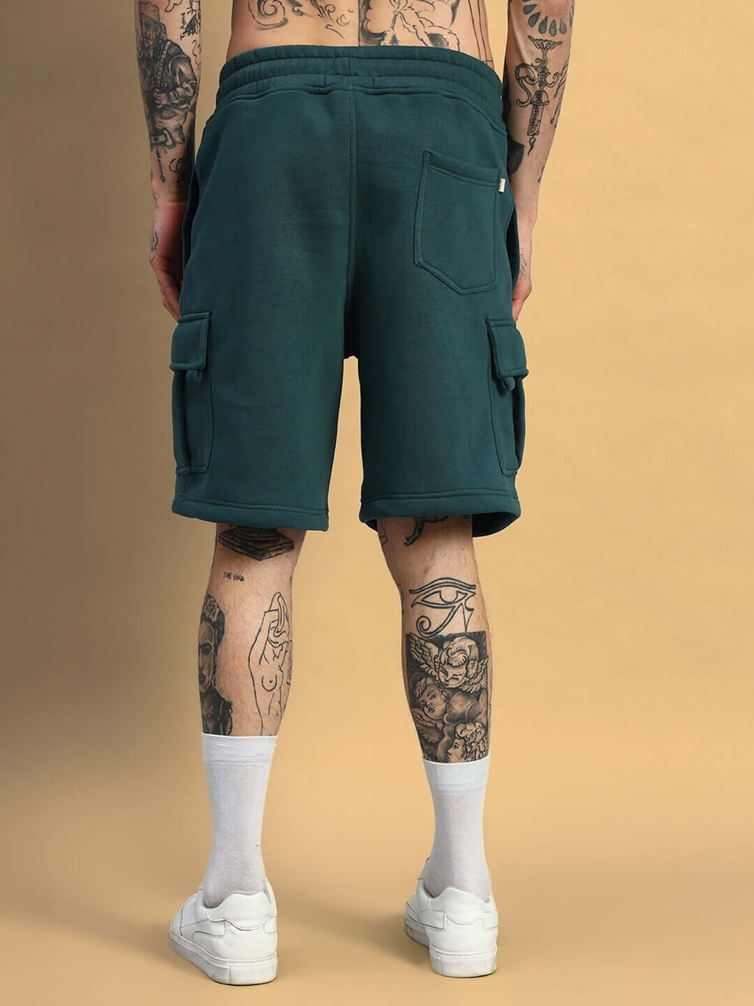 Back view of HUSKY FLEECE SOLID CARGO SHORTS TEAL GREEN on tattooed model, showcasing comfortable fit and functional pockets.