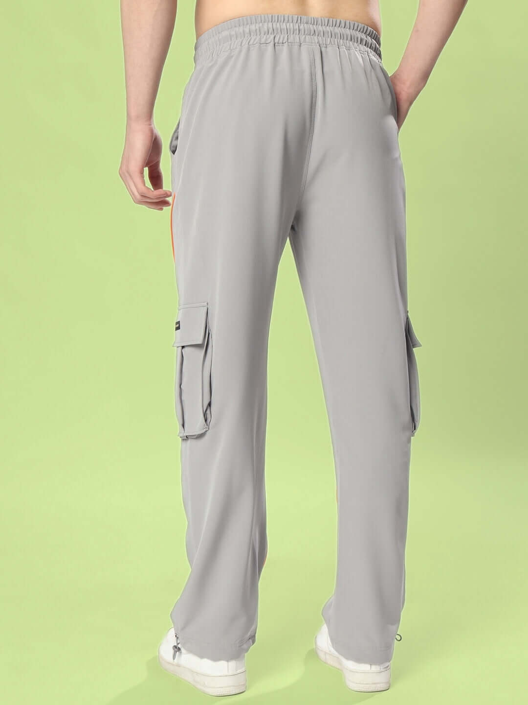 Back view of HYPEBEAST grey cargo pants with neon orange accents on a green background.