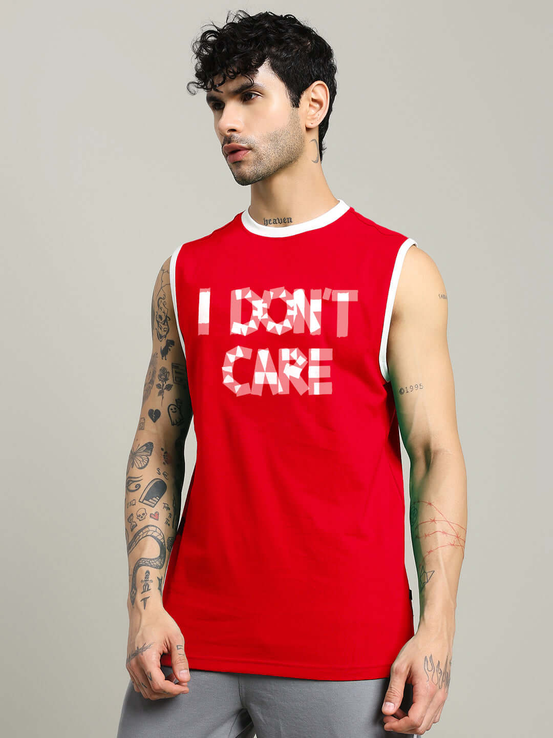 Man wearing a red 'I DON’T CARE' gym t-shirt with tattoos on arms, offering customizable sizing options for personalized fit and comfort.