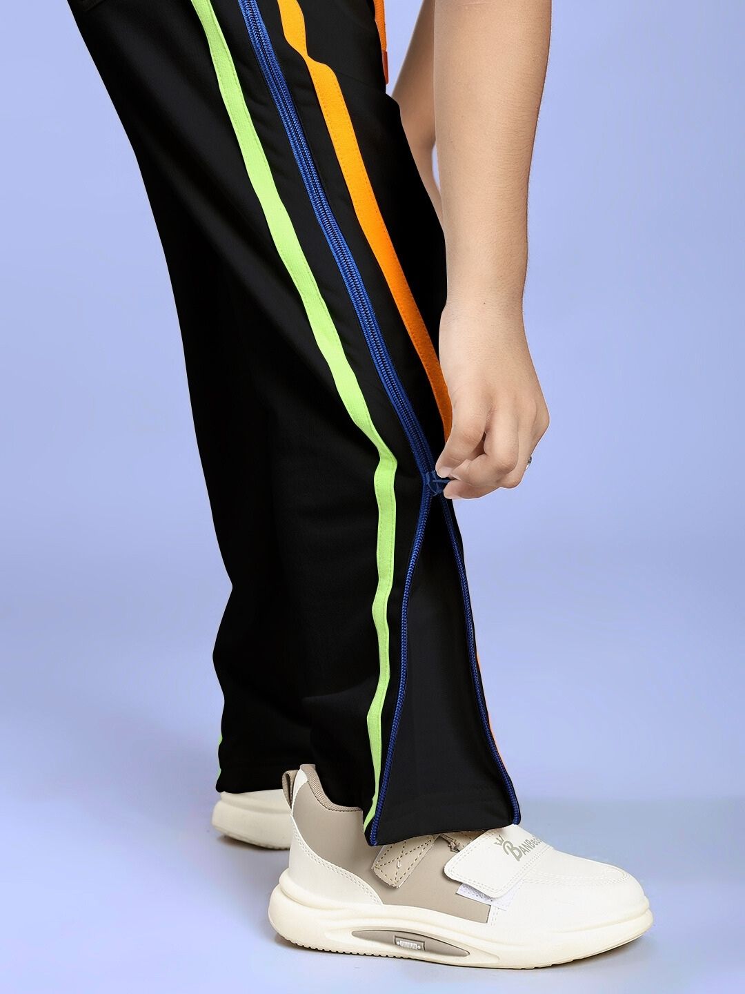 Side view of a child wearing IMPERIAL SIDE ZIPPER JOGGER FOR BOYS AND GIRLS BLACK showing colorful stripes and side zipper detail.