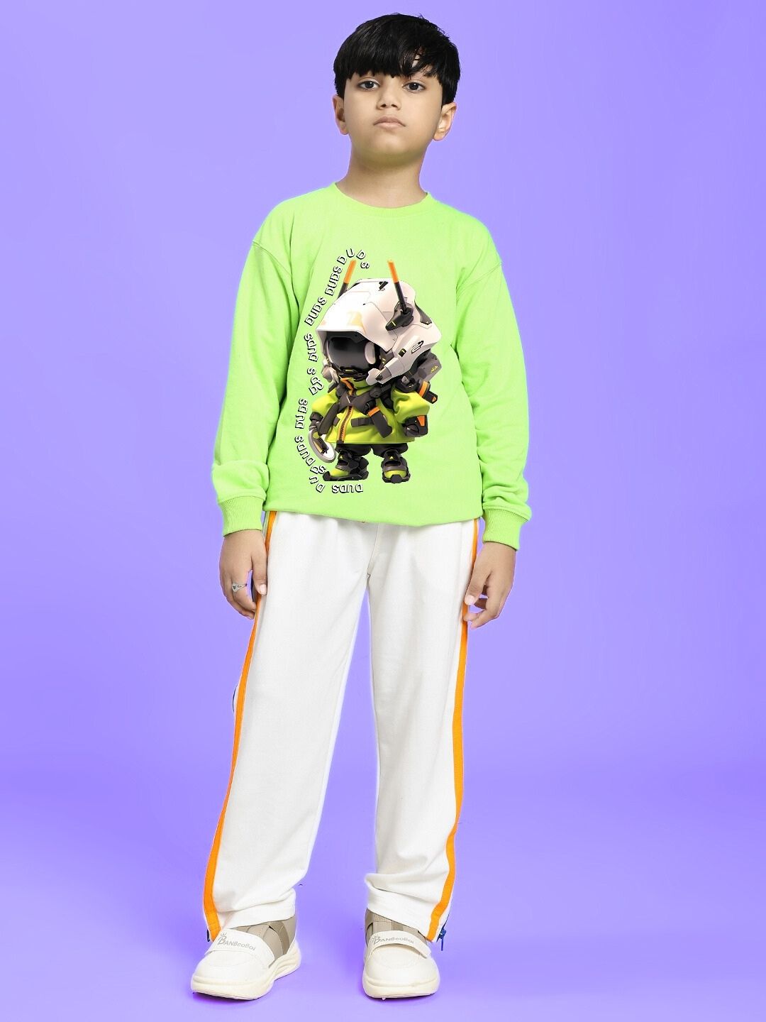 Child wearing IMPERIAL SIDE ZIPPER JOGGER FOR BOYS AND GIRLS OFF WHITE with green shirt, standing on purple background.