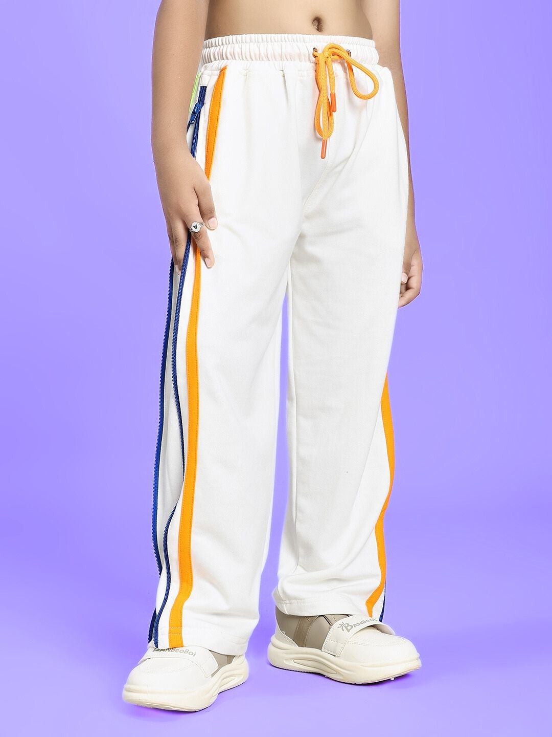 Child wearing IMPERIAL SIDE ZIPPER JOGGER FOR BOYS AND GIRLS OFF WHITE with orange and blue stripe detail.