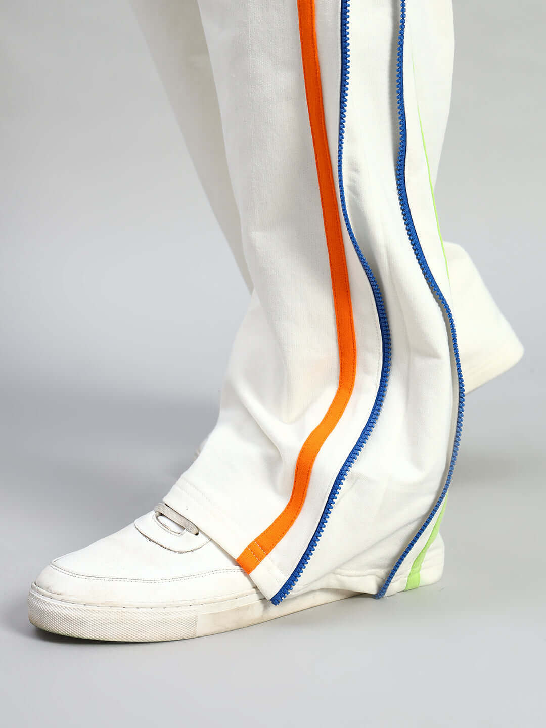 Off white joggers with colorful side zippers and white sneakers, showcasing a stylish and trendy look.