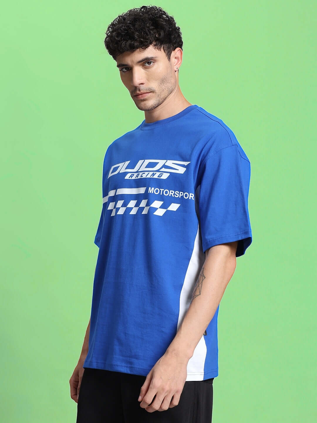 Man wearing INDY OVER-SIZED CLASSIC T-SHIRT ROYAL BLUE with motorsport design.