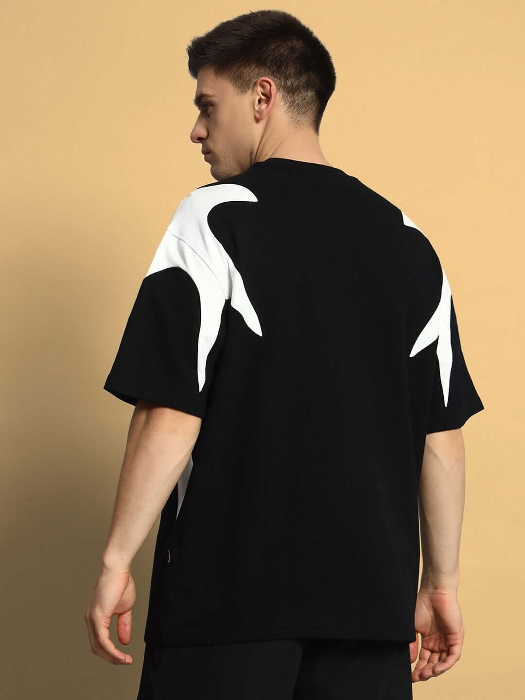 Back view of a black oversized Infinity Saga T-shirt made from premium heavy gauge fabric, featuring white design elements on the sleeves.