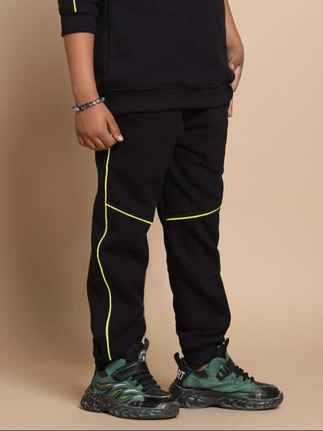 Child wearing INNOCENT black jogger pants with neon green accents, suitable for boys and girls, showcasing comfortable style.
