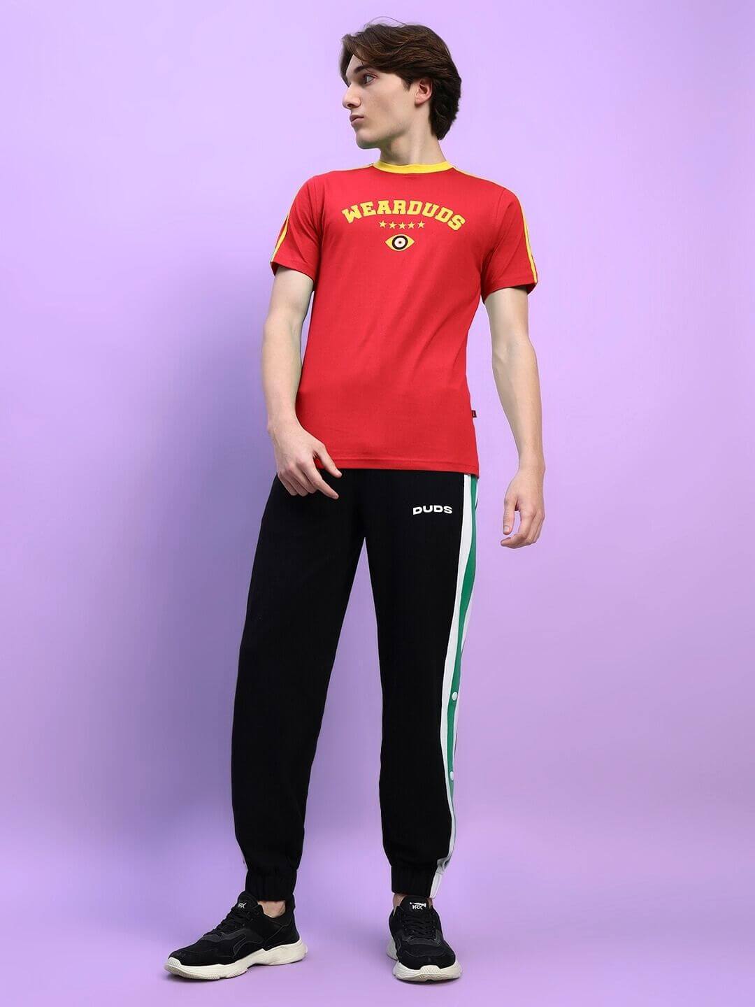 Person wearing an IRISH REGULAR FIT T-SHIRT IN RED with black pants, displaying casual style against a purple backdrop.