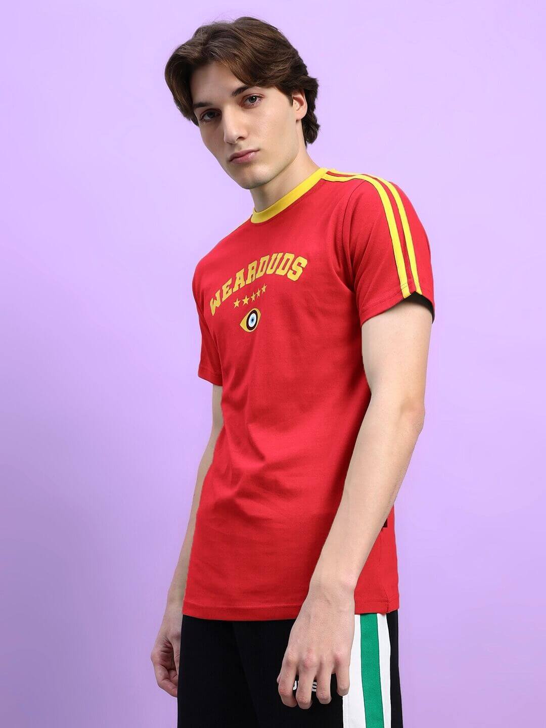 Model wearing Irish Regular Fit T-Shirt in red with yellow stripes and emblem on chest, styled with black shorts.