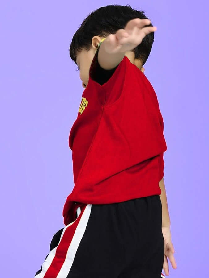 Child wearing IRISH T-SHIRT FOR BOYS AND GIRLS RED with vibrant color and Irish-themed detailing, showcasing a playful style against a purple background.