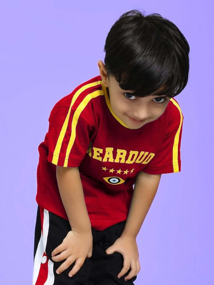 Child wearing a red IRISH T-SHIRT FOR BOYS AND GIRLS RED with yellow stripes, posing against a purple background.