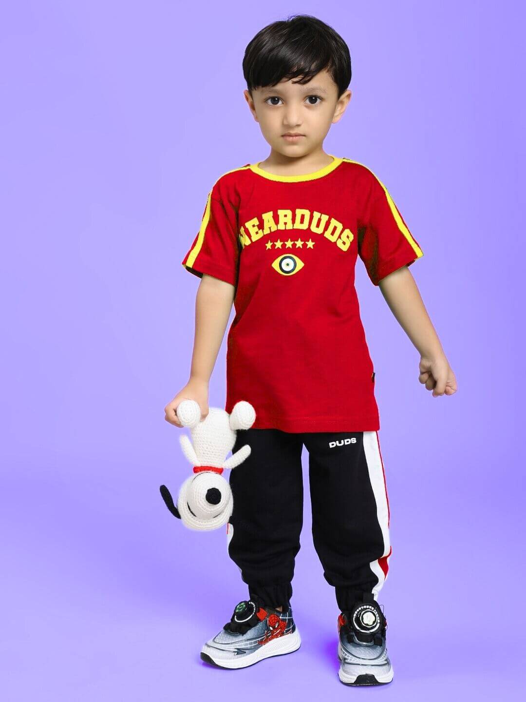 Child wearing IRISH T-SHIRT FOR BOYS AND GIRLS RED with graphic design, holding a stuffed toy, against a purple background.