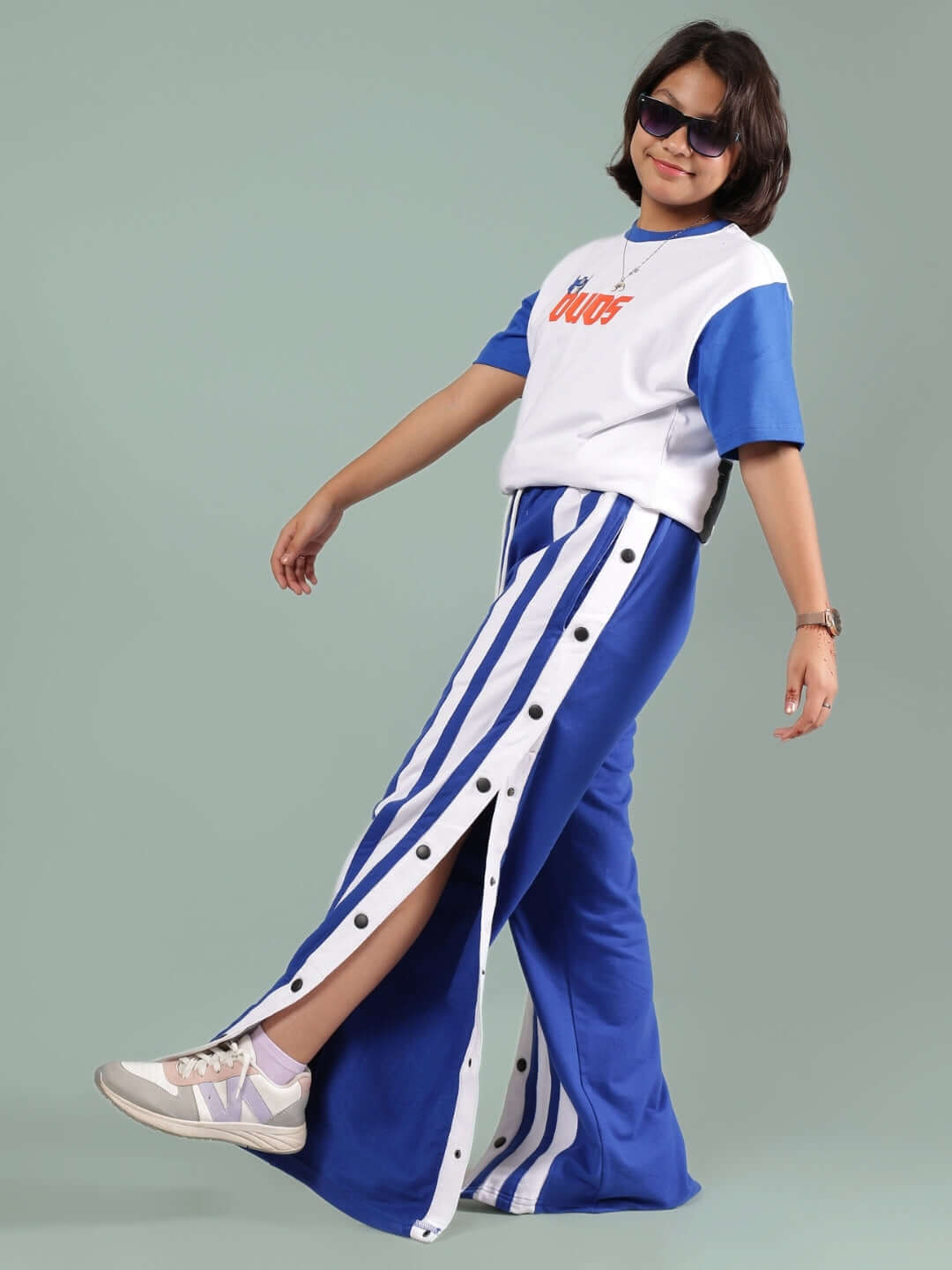 Child wearing IRONA Co-ord set for boys and girls, white top with blue sleeves, and blue-striped pants, by DUDS.