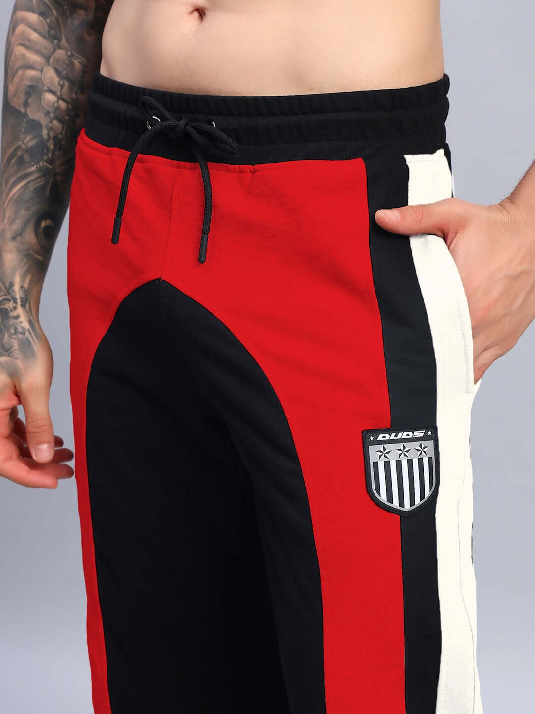 Model wearing JAMISON COLOR BLOCK RELAXED-FIT JOGGERS BLACK RED with vibrant contrast panels, streetwear fashion detail.
