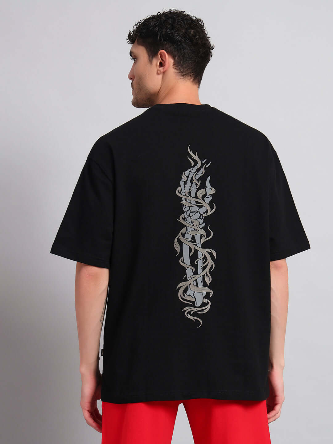 JELVIN over-sized black T-shirt with unique back design, made from premium cotton and elastane, worn by model viewed from behind.