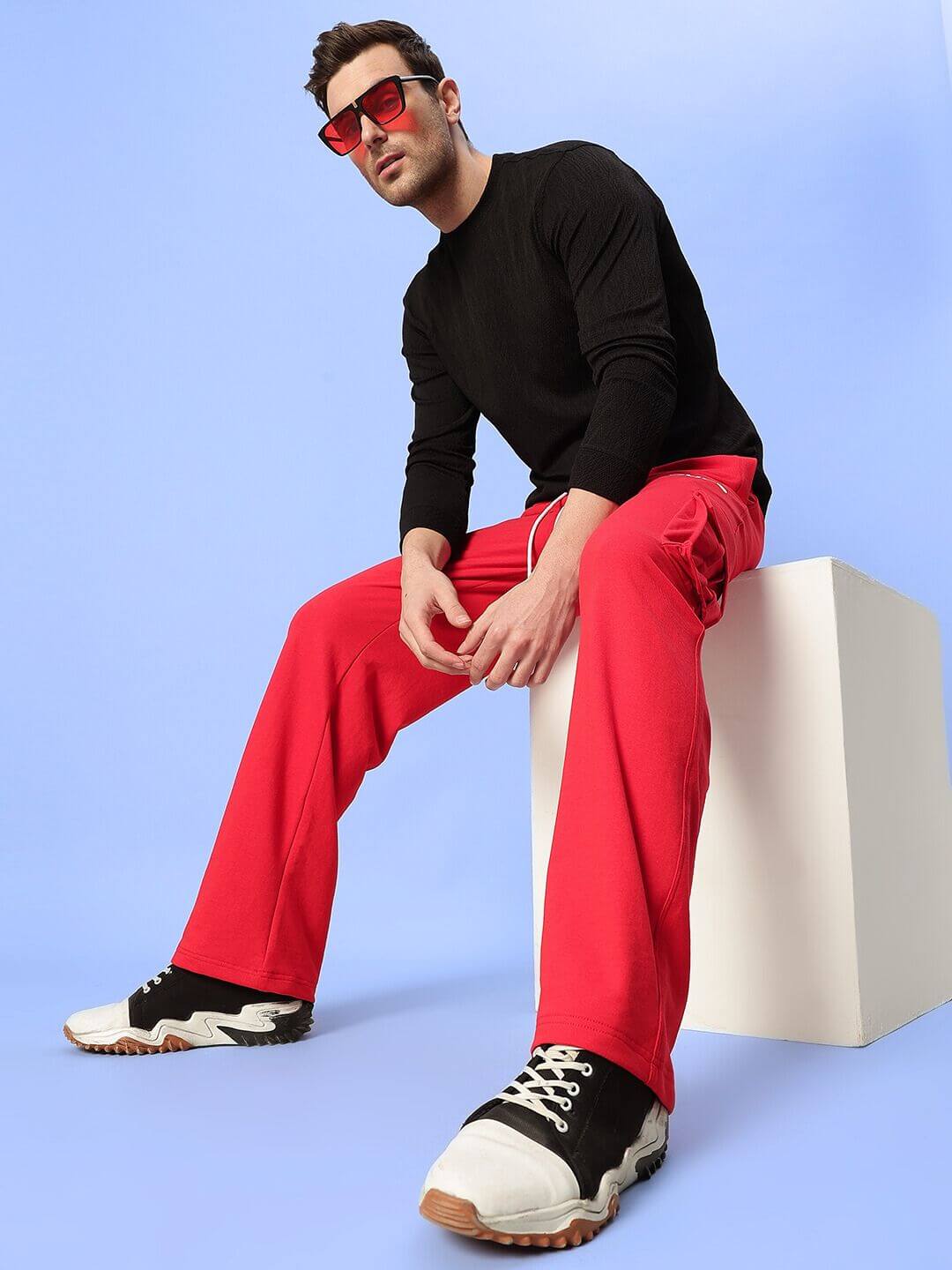 Model wearing JESS 5 POCKET RELAXED FIT JOGGERS RED with black sweater and sneakers, showcasing comfortable streetwear style.