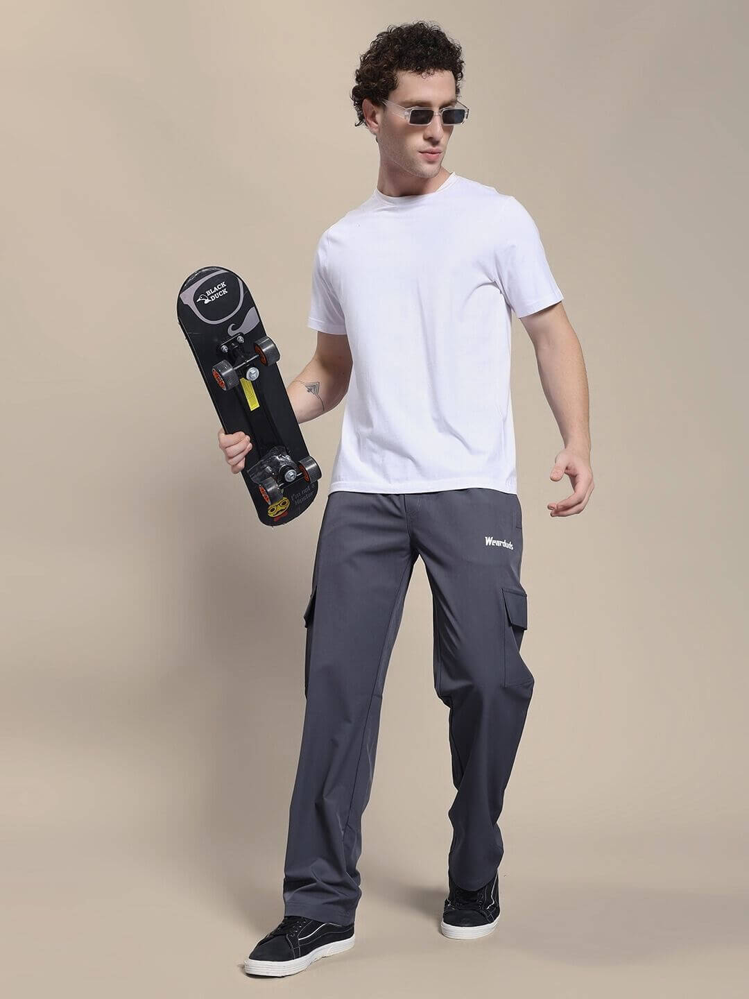 Man wearing JIMMY RELAXED FIT MULTI POCKET JOGGER DARK GREY holding a skateboard