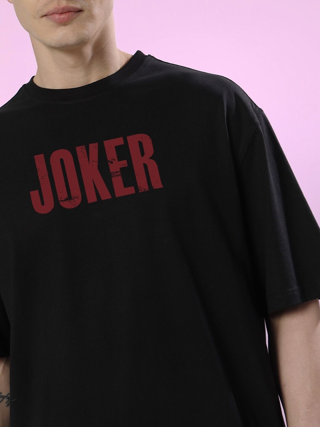 Close-up view of JOKER PRINTED OVERSIZED T-SHIRT BLACK featuring red text on a black shirt.