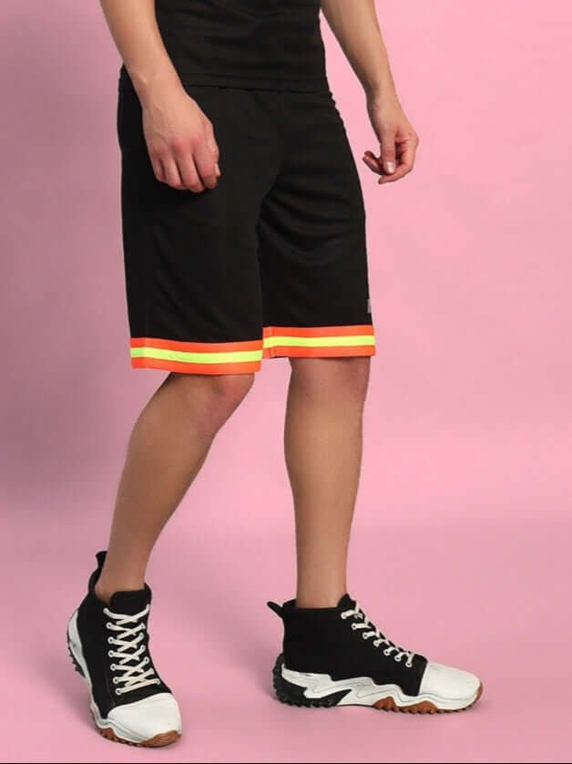 Person wearing JORDAN REGULAR FIT SHORTS BLACK standing with hands by sides on pink background.