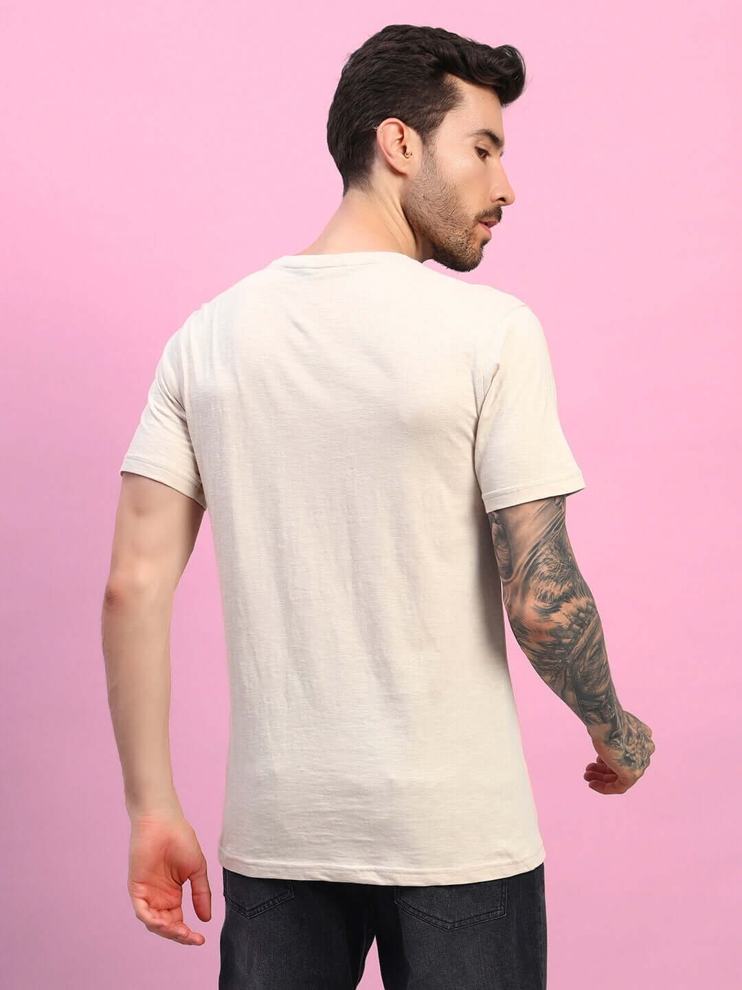 Back view of JOY Regular Fit Beige T-Shirt in premium heavy cotton slub fabric, worn by a model against a pink background.